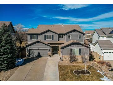 Beautiful two-story home featuring manicured landscaping, gray siding, and a concrete driveway leading to an attached two-car garage at 11043 Valleybrook Cir, Highlands Ranch, CO 80130