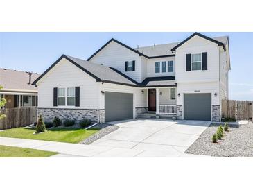 Charming two-story home showcasing a landscaped front yard and a double garage, perfect for modern living at 5840 Longs Peak St, Brighton, CO 80601