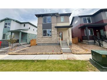 Charming two-story home featuring stone accents and a well-manicured lawn at 21152 E 63Rd Dr, Aurora, CO 80019