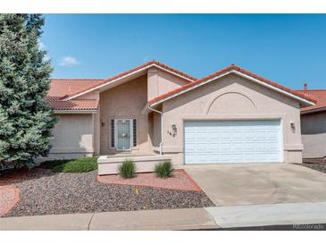 Charming home featuring a terracotta roof, manicured landscaping, and an attached two-car garage at 160 Las Lunas St, Castle Rock, CO 80104