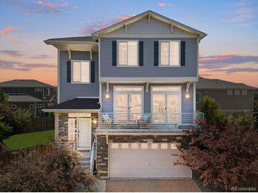 Charming two-story home featuring a welcoming front porch and a well-maintained yard at sunset at 239 S Old Hammer St, Aurora, CO 80018