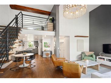 Inviting living room featuring high ceilings, modern chandelier, wood floors, and open staircase to the second floor at 505 Detroit St, Denver, CO 80206