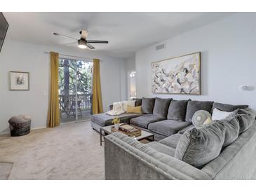 Bright living room featuring a large grey sectional sofa, ceiling fan, and sliding glass doors to the deck at 1671 W Canal Cir # 221, Littleton, CO 80120