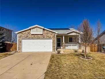 Charming home with a stone facade, white garage door, and a well-maintained front yard with mature landscaping at 12555 Birch Ave, Thornton, CO 80241