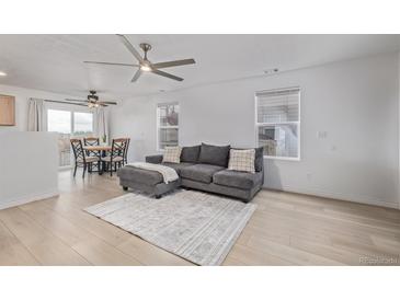 Bright living room with hardwood floors, a ceiling fan, and a comfortable gray sofa at 649 Mockingbird St, Brighton, CO 80601