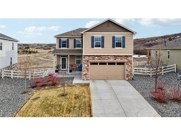 Inviting two-story home with stone accents, a well-maintained lawn and a two car garage at 2042 Shadow Creek Dr, Castle Rock, CO 80104