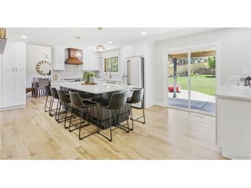 Bright kitchen with white cabinets, an island with seating, and stainless steel appliances at 9810 Venneford Ranch Rd, Highlands Ranch, CO 80126