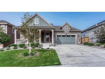 Charming home with a welcoming porch, well-manicured lawn, and two car garage for a lovely curb appeal at 6930 Hyland Hills St, Castle Pines, CO 80108