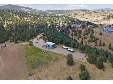 Expansive aerial view of a property with a large blue barn, vineyard, sheds, and surrounding wooded hills at 1044 S Grapevine Rd, Golden, CO 80401