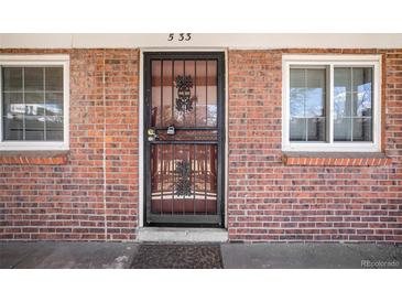 A brick facade with secure black iron door and surrounding windows provides a classic look to the home's entrance at 6800 E Tennessee Ave # 533, Denver, CO 80224