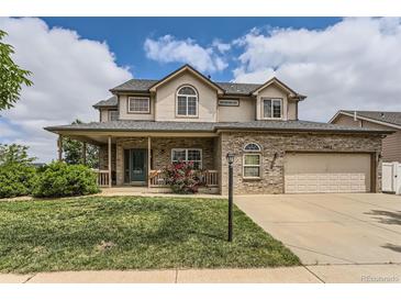 Charming two-story home featuring a covered front porch, brick accents, an attached garage, and a well-manicured lawn at 5483 Gunnison Dr, Frederick, CO 80504