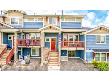 Inviting blue townhome featuring stone accents, red door and trim, and a cozy, railed balcony at 619 Brennan Cir, Erie, CO 80516