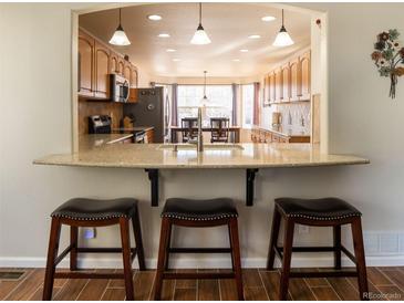 Bright kitchen pass through with bar stool seating and natural light at 1128 S Duquesne Cir, Aurora, CO 80018