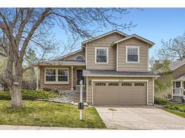 Inviting tan two-story home showcasing a two-car garage and well-manicured lawn at 6382 Freeport Dr, Highlands Ranch, CO 80130