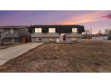 Two-story home with red door, neutral siding, and a well-maintained, xeriscaped front yard at dusk at 206 Cedar St, Hudson, CO 80642