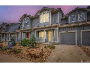 Charming townhome featuring a gray exterior, landscaped front yard, and attached one-car garage at 226 Ash St, Bennett, CO 80102