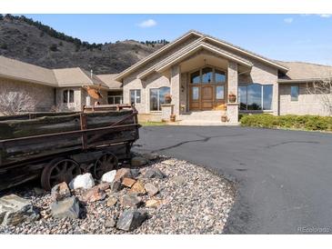 Beautiful brick home featuring professional landscaping and a circular driveway in front of a mountain backdrop at 5881 Deer Meadow Trl, Golden, CO 80403
