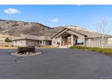 Inviting brick home featuring a circular driveway with unique vintage wagon wheel accent and mountain views at 5881 Deer Meadow Trl, Golden, CO 80403