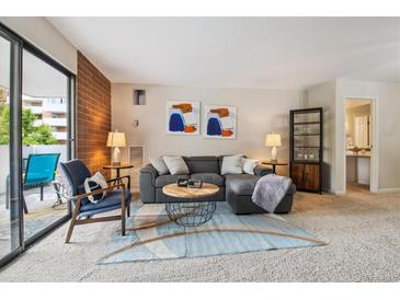 Inviting living room features a comfortable gray sectional, stylish decor, and access to a private balcony at 2880 S Locust St # 305N, Denver, CO 80222