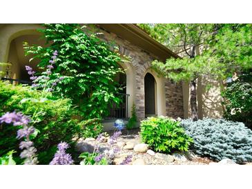 Charming home entrance with stone facade, lush greenery, and vibrant flowers. Great curb appeal! at 10328 Bluffmont Dr, Lone Tree, CO 80124