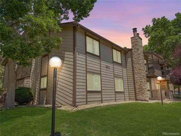 Exterior view of home with brown siding, a stone chimney, and manicured lawn at 1870 S Pitkin Cir # B, Aurora, CO 80017