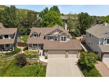 Charming two-story home with a three-car garage, manicured landscaping, and mature trees at 2146 S Ellis Ct, Lakewood, CO 80228