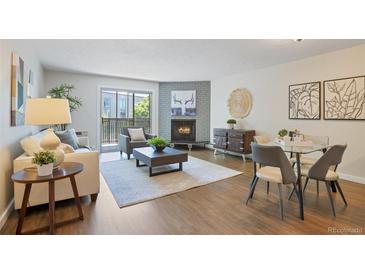 Inviting living room with a fireplace, balcony access, and warm wooden floors at 3470 S Poplar St # 404, Denver, CO 80224