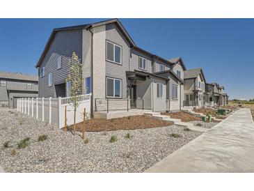 New townhome showcasing a modern exterior with gray siding, painted brick accents, and landscaped front yard on a sunny day at 1290 S Algonquian St, Aurora, CO 80018