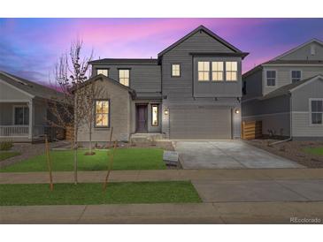 Two-story gray home featuring a two-car garage, manicured lawn, and inviting front entrance at 9973 Worchester St, Commerce City, CO 80022