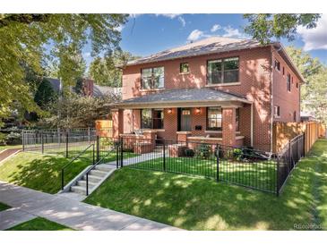 Brick two-story home with landscaped yard and black fence at 2063 Cherry St, Denver, CO 80207