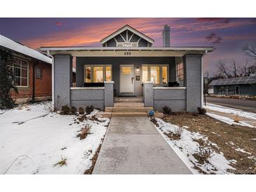 Charming gray brick home featuring a covered porch and beautiful landscaping at 595 N Lafayette St, Denver, CO 80218