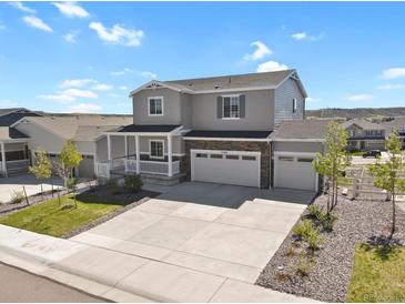 Two-story home with a welcoming porch, a spacious driveway, and a manicured front yard at 5166 Trails Edge Ln, Castle Rock, CO 80104