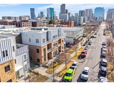 Modern townhomes with brick and metal exteriors in a vibrant cityscape with tree lined street and sidewalks at 2530 Lawrence St # Ra101, Denver, CO 80205