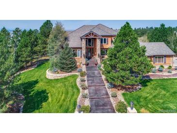 Beautiful two-story home showcasing a sprawling manicured lawn and a lengthy walkway to the front door at 5449 Songbird Way, Parker, CO 80134