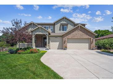 Charming two-story home with brick accents, a well-manicured lawn, and a two-car garage at 3890 Tabor Ct, Wheat Ridge, CO 80033