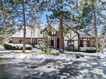 Charming home exterior featuring a stone and stucco facade, mature trees, and snowy landscaping at 30544 The Golf Club Point, Evergreen, CO 80439