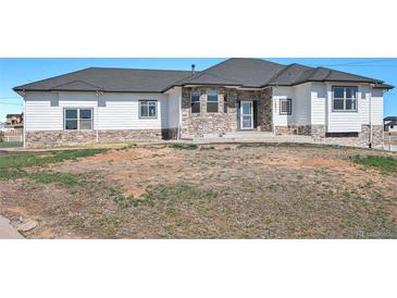 Charming single-story home boasts a stone-accented facade, white siding, and a beautifully landscaped front yard at 10071 E 142Nd Ave, Brighton, CO 80602