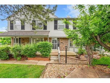 Charming townhome featuring a mix of brick and siding, complemented by lush greenery and mature trees at 9930 W Progress Pl, Littleton, CO 80123