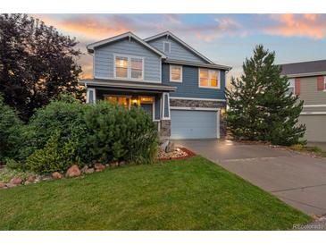 Charming two-story home with blue siding, stone accents, lush landscaping, and an attached two-car garage at 19067 W 57Th Dr, Golden, CO 80403