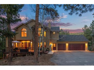 Stunning multi-story home with a three-car garage nestled in a wooded landscape with a deck at 7192 Pinewood Dr, Evergreen, CO 80439