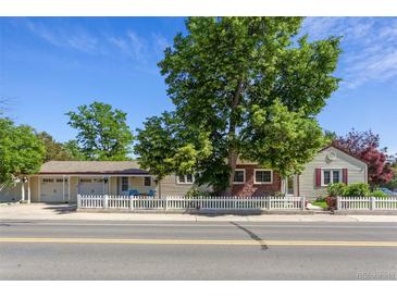 Charming home with a white picket fence and a mature tree in front of the home at 8001 W 57Th Ave, Arvada, CO 80002