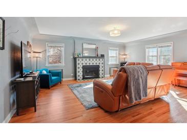 Cozy living room with hardwood floors, fireplace, and comfortable seating, offering a relaxing atmosphere at 8001 W 57Th Ave, Arvada, CO 80002