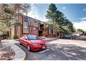 Brick and wood condo building with visitor parking and mature landscaping for a welcoming curb appeal at 420 Wright St # 101, Lakewood, CO 80228