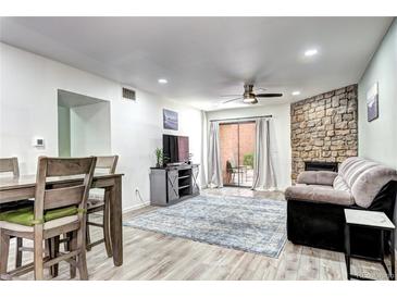 Bright living room with a stone fireplace, ceiling fan, wood-look floors and sliding glass doors to the patio at 420 Wright St # 101, Lakewood, CO 80228