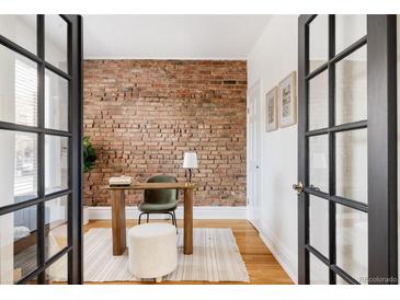 Charming home office with exposed brick wall, wood desk, and natural light streaming through glass doors at 1000 N Ogden St, Denver, CO 80218