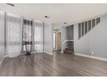Bright living room features large windows with sheer curtains and gray wood-look flooring at 4950 Homestead Pl # 23, Thornton, CO 80229