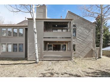 Exterior view of a two-story condo featuring double balconies, a wood-paneled facade, and mature trees at 23561 Genesee Village Road # C, Golden, CO 80401