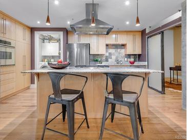 Modern kitchen boasts stainless appliances, center island with seating, and unique backsplash at 1449 Wynkoop St # 305, Denver, CO 80202