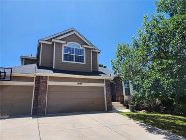 Two-story home featuring a three-car garage, brick accents, and a well-maintained front yard with a large tree at 10089 Wynwood Way, Highlands Ranch, CO 80126