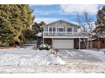 Two-story house with attached garage and deck, nestled in a snowy landscape at 3420 S Nucla Way, Aurora, CO 80013